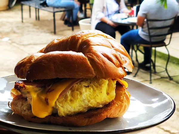Croissant relleno de huevo, jamón, tocino y queso amarillo derretido.